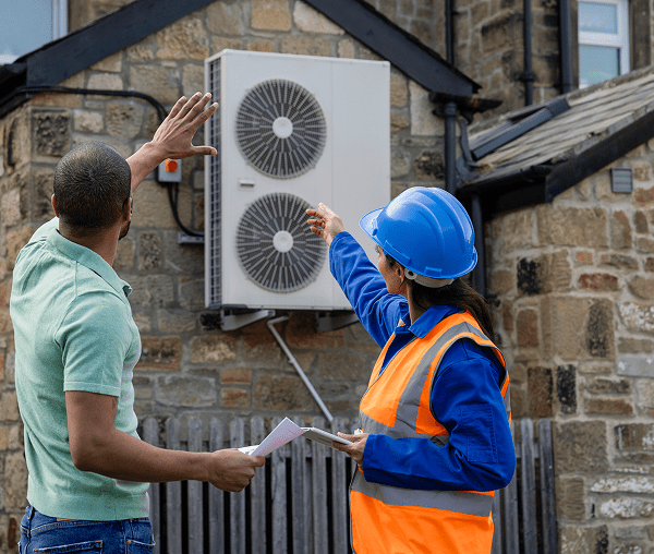 Technician and homeowner inspecting air conditioning unit.