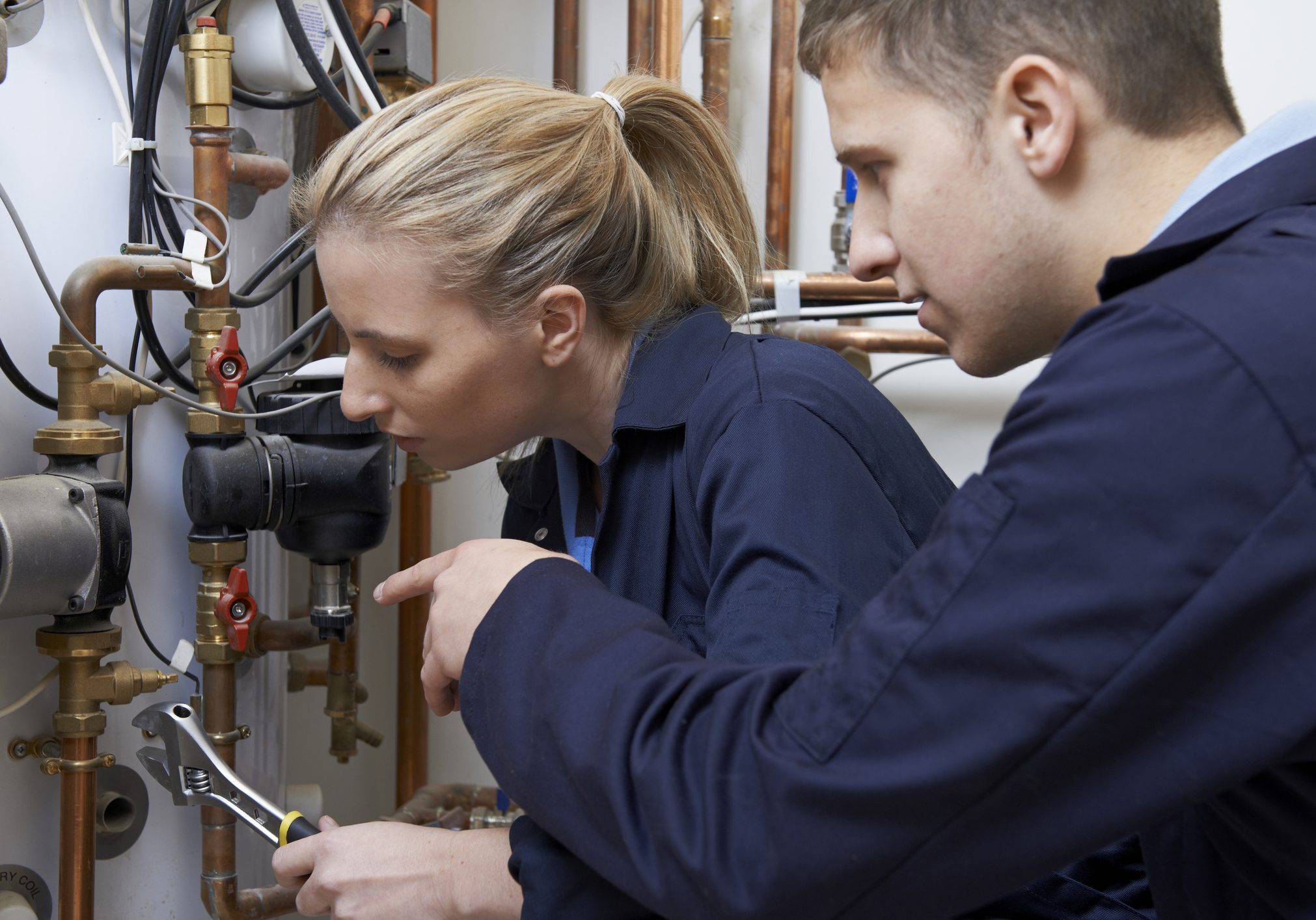 Female Trainee Plumber Working On Central Heating Boiler